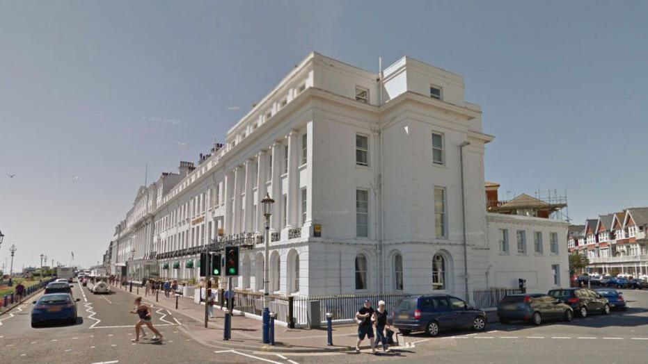 An image of of a large white regency-style building on a seafront in Eastbourne