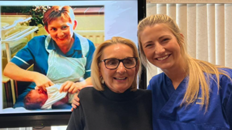 Katie Wintle, on the right, with colleague Sharon Cooling. Behind them is a screen showing an image of Ms Cooling holding Ms Wintle as a newborn baby