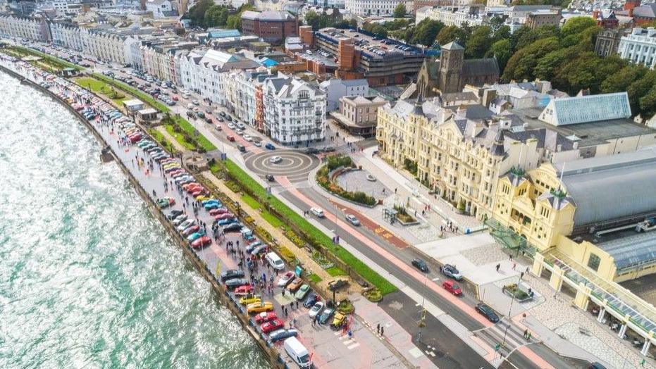 An aerial view of Douglas Promenade with hundreds of colourful cars lined up on the seafront.