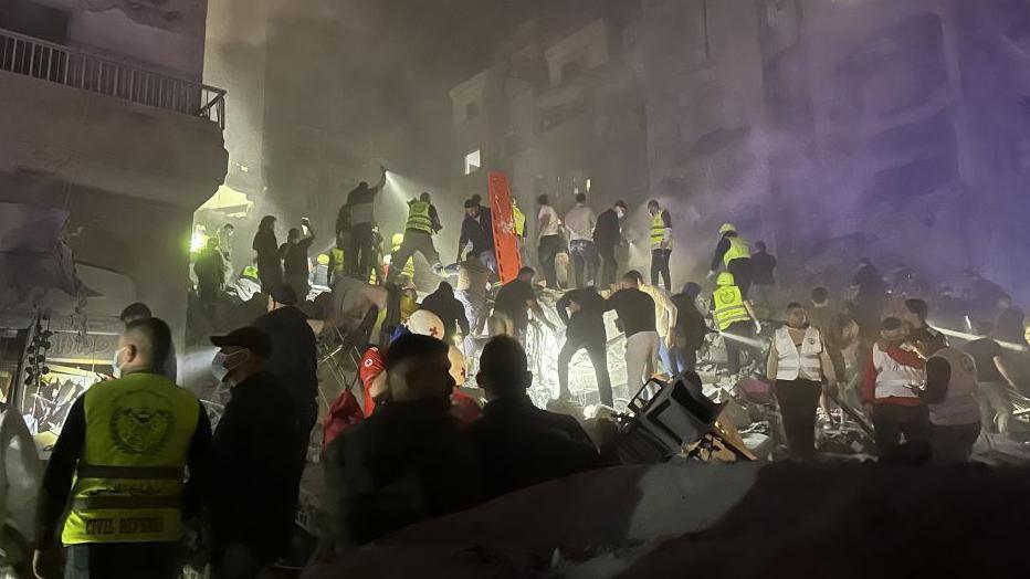 A night scene as rescue workers rush to clear wreckage and find survivors following a massive Israeli airstrike in central Beirut. They are working by torch and floodlight.