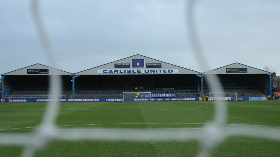 A view of the Warwick Road terrace at Carlisle's Brunton Park ground from through the netting at the other end
