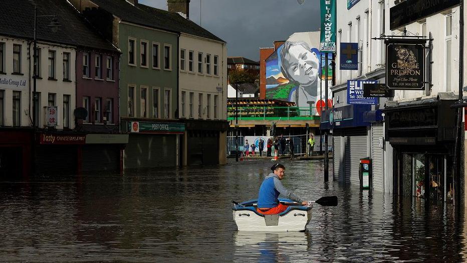 A man paddles a boat past shopfronts on Sugar Island last Halloween