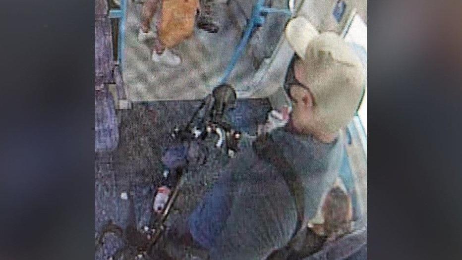 A man on a train with a face mask and hat on holding a bycycle