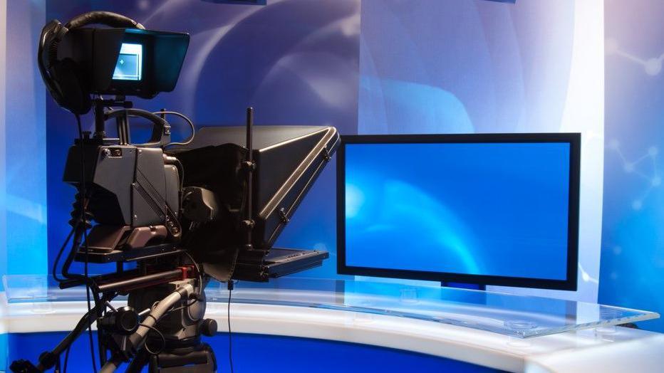 A generic image of a news studio with blue screens and a camera