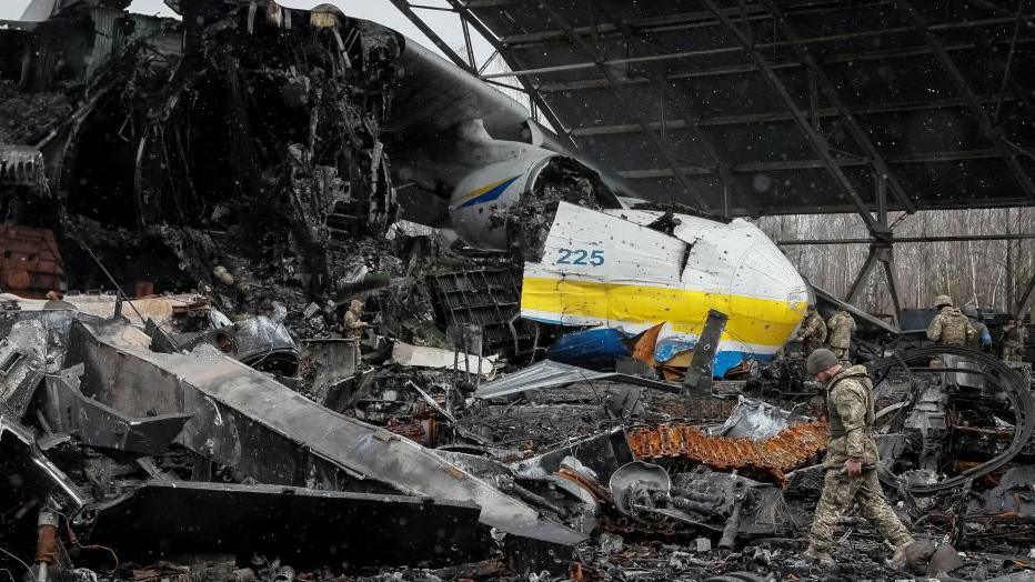 A Ukrainian service member walks in a front of the Antonov An-225 Mriya cargo plane, the world's biggest aircraft, destroyed by Russian troops as Russia's attack on Ukraine began in February 2022.