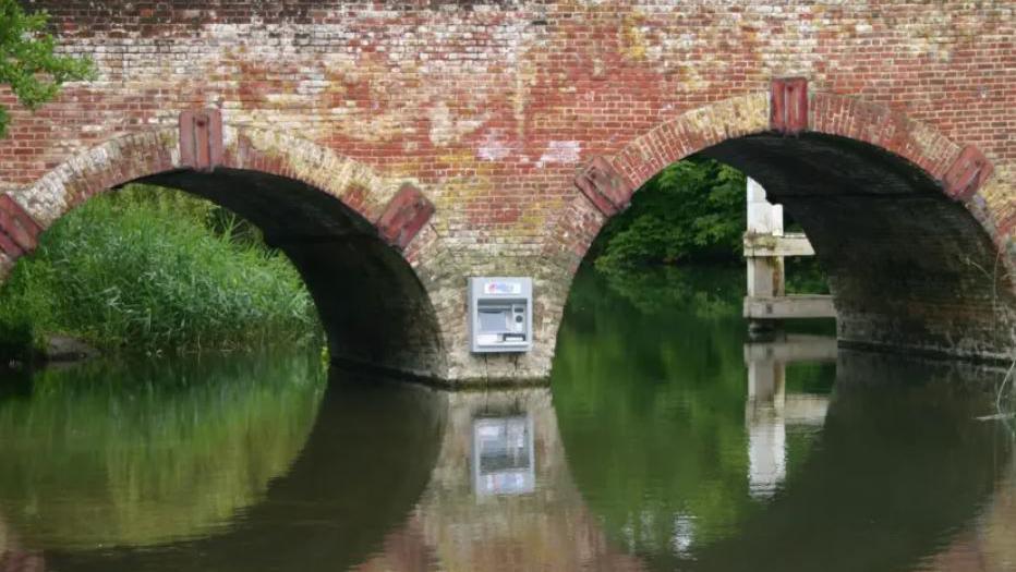 A cash machine on the side of a bridge, placed between its two arches, but inaccessible to anyone (unless they were on the river).