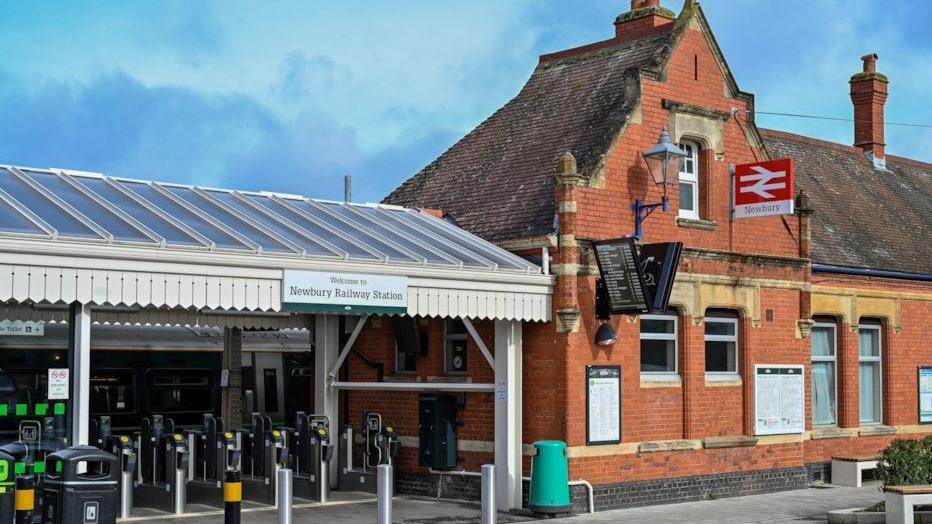 Exterior of Newbury railway station, a brick building with ticket barriers.