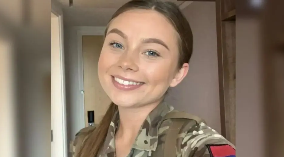 Young woman in camo gear and brown hair smiling at the camera