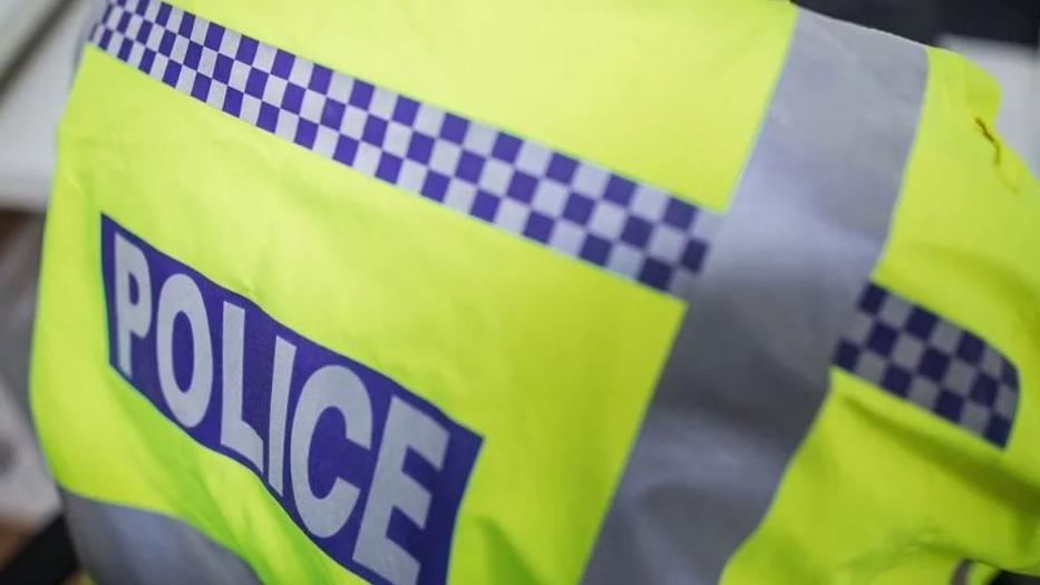 A close up shot of a yellow high-vis jacket with the word police written on it.