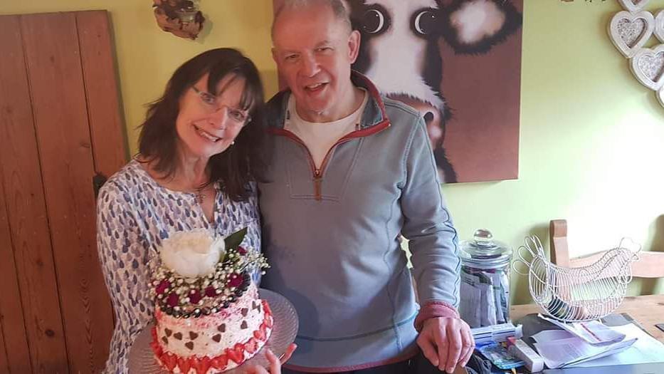 Martyn and Lynn Hall smiling, holding a cake