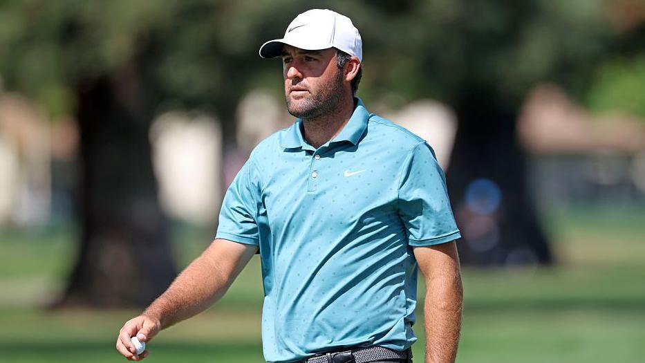 Scottie Scheffler wearing a white baseball cap and blue T-shirt