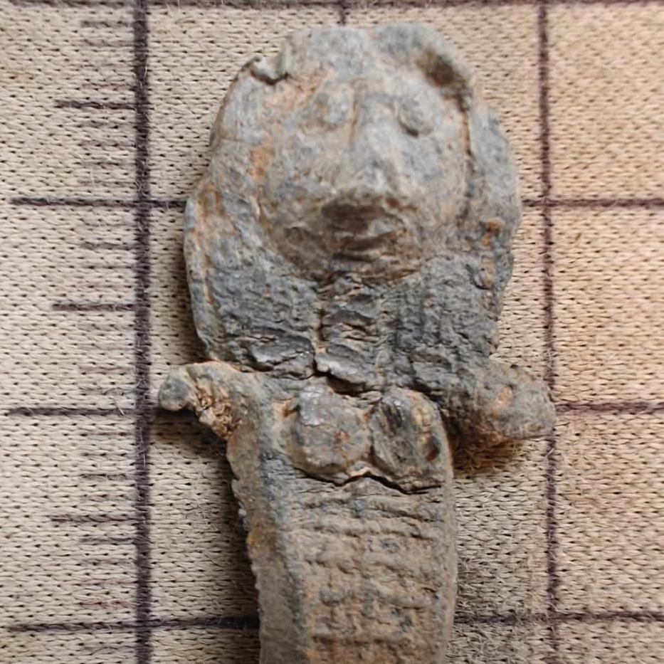 A close up picture of the medieval doll. Hair and eyes are easy to make out as well as short arms and breasts.