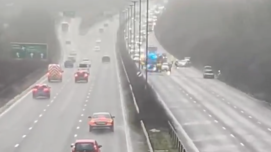 An image showing six lanes of the A27 and on the right hand side there is a queue of traffic behind the blue lights of a fire engine and a car parked off to the side near the hard shoulder.