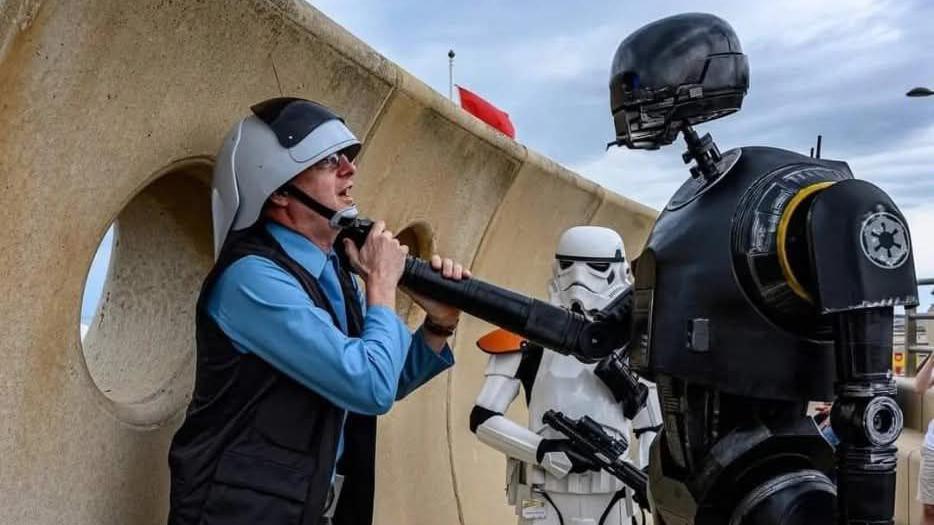 A fan is held by the throat by replica of droid K-S20 at the spot replicating a scene from Andor