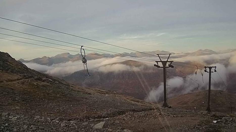 The ski tows and cables are free of ice and the snow has disappeared from the rocky ground below and the mountains beyond.