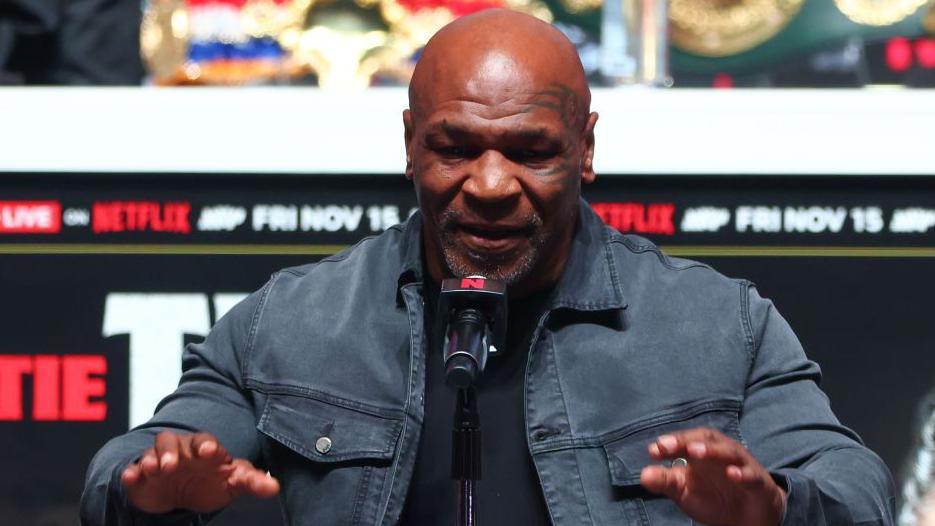 Mike Tyson raises his hands as he answers a question at a news conference