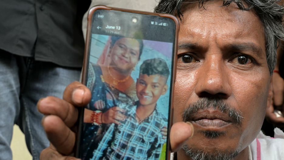 Suresh Patni, father of Akash Patni, a victim of the Air India Flight 171 crash, shows a photograph of his wife (L) and deceased son