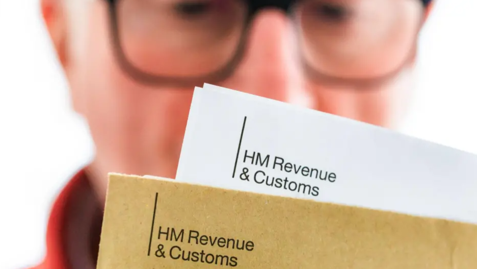 Man in glasses in the background looking at government tax letters in the foreground