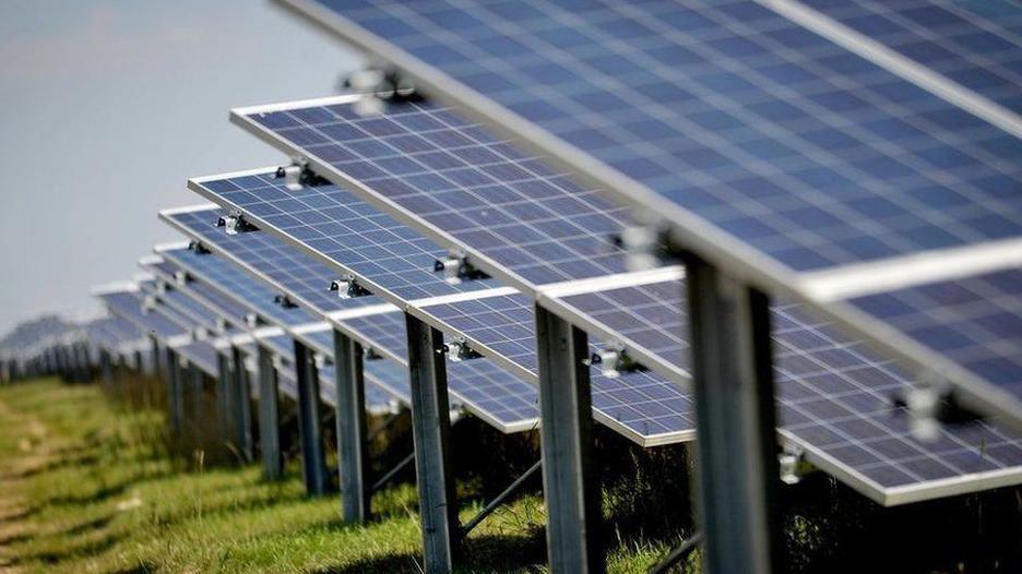 A row of blue solar farm panels located in a field.