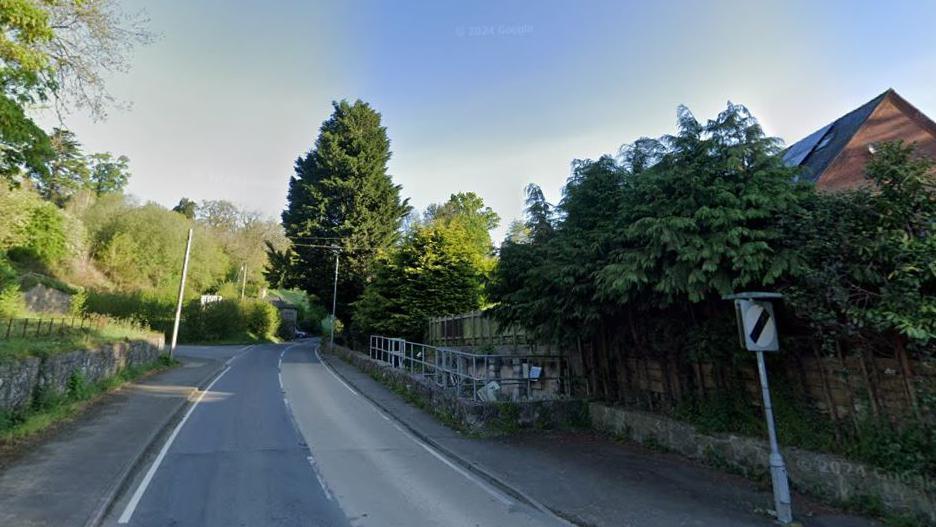 Google Street view image of A490 road taken in summer with trees to the right and left of road 