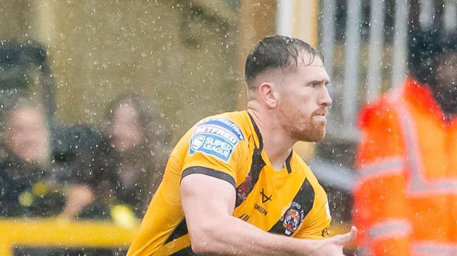Rowan Milnes playing in the rain for Castleford, having just passed the ball