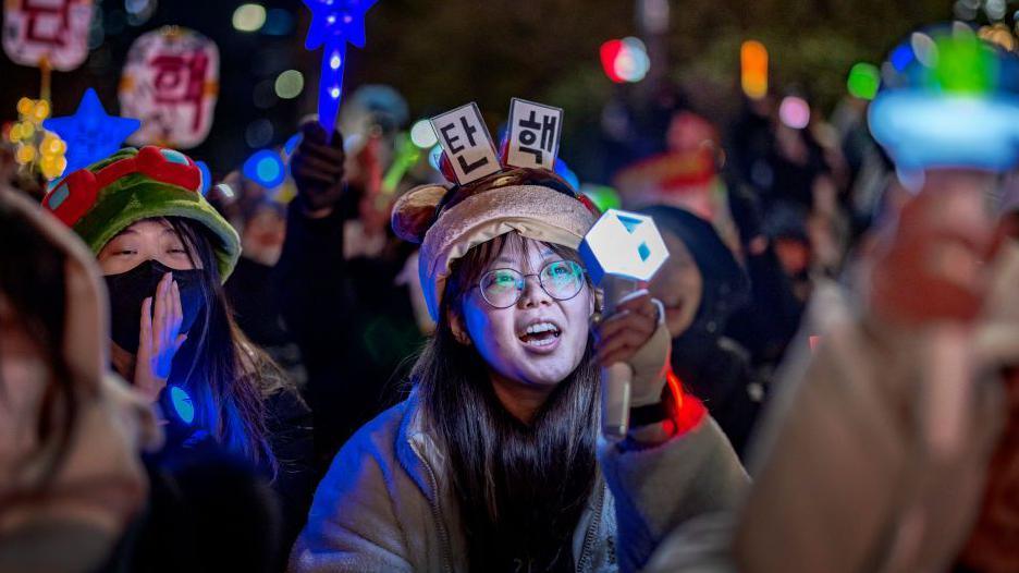Protesters wave K-pop light sticks as they take part in a protest against the president outside the National Assembly on December 08, 2024 in Seoul
