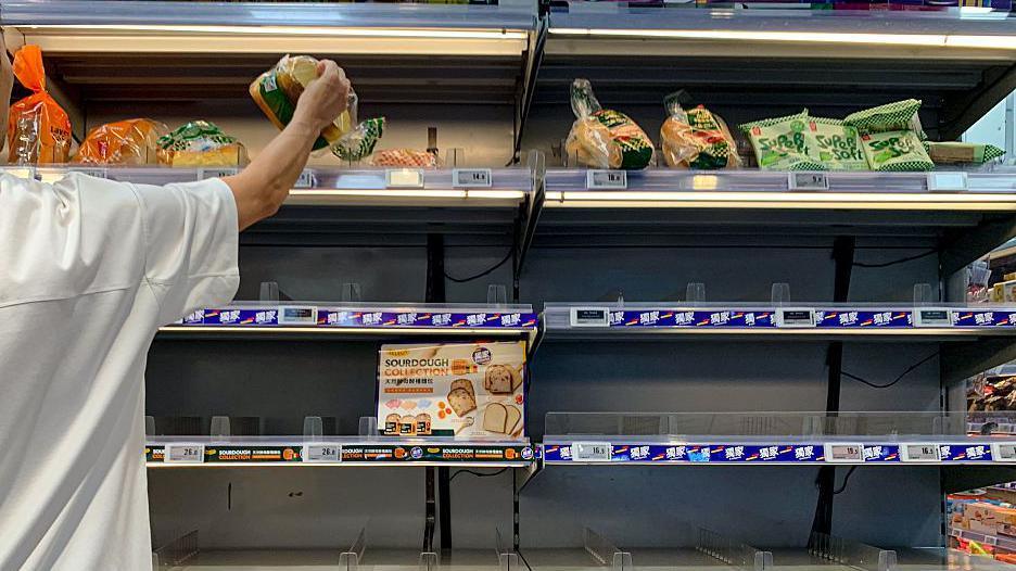 A man picks up a bread from nearly-empty shelves on 22 September in Hong Kong, China