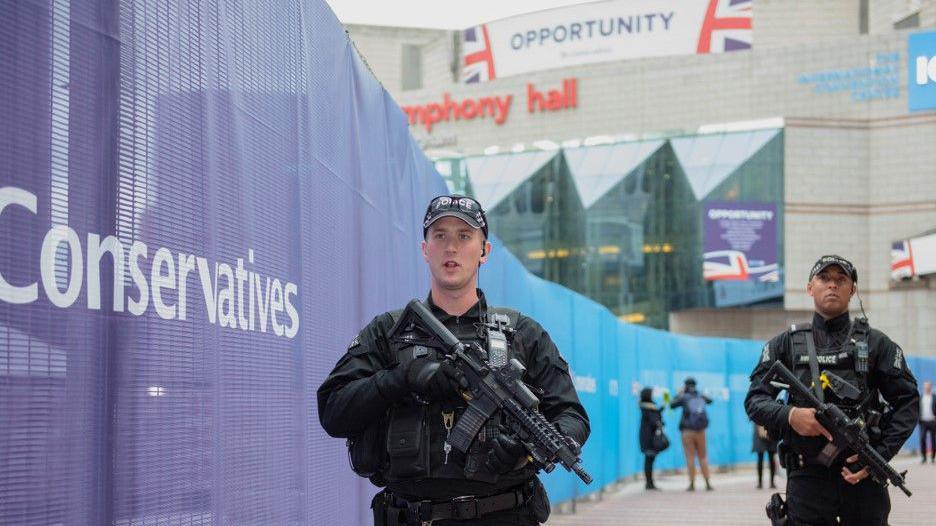 Two armed policemen dressed in black holding a gun