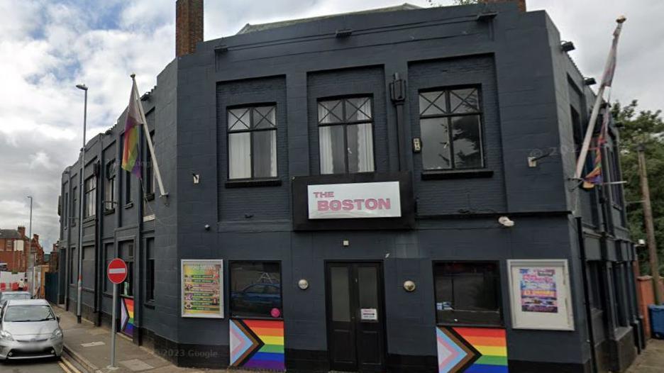 Boston Bar in Northampton, a black building with LGBTQ+ flags