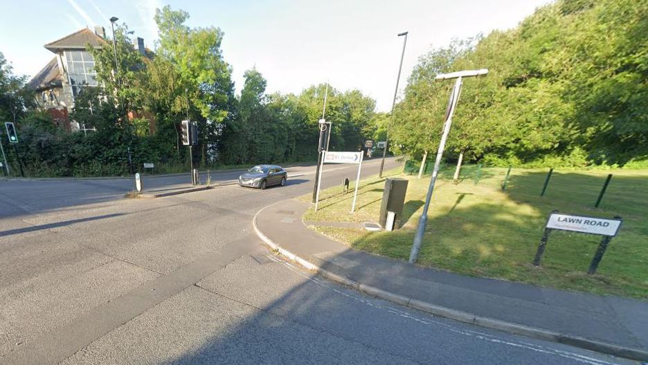 Road junction with traffic lights and trees along the sides.