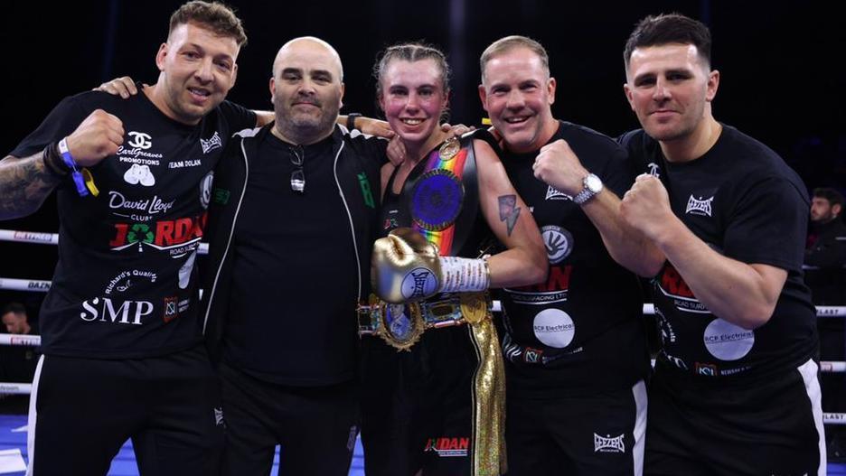 Emma Dolan poses with her team wearing the British title belt in the boxing ring at Birmingham.