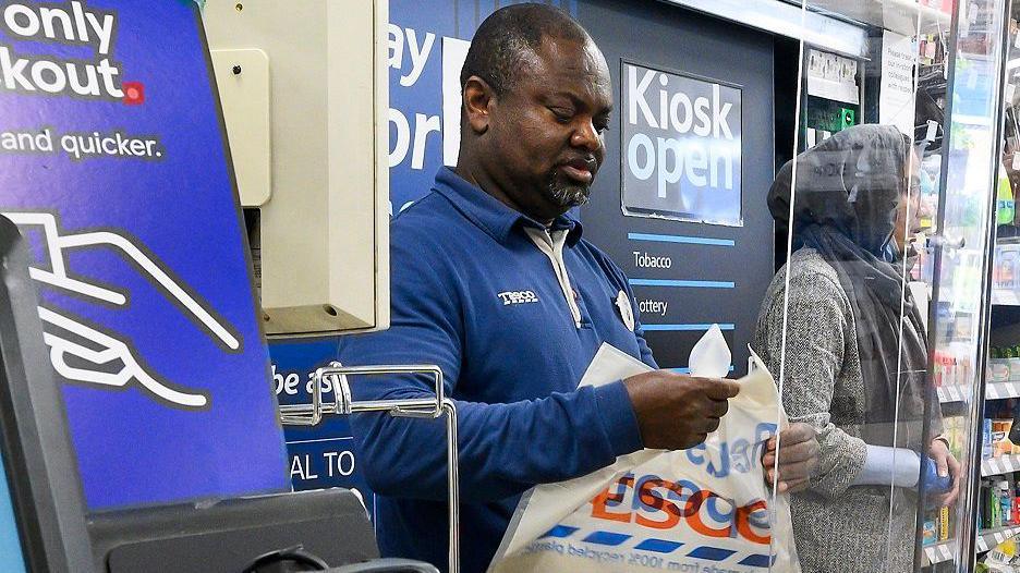 A Tesco cashier working at the till 