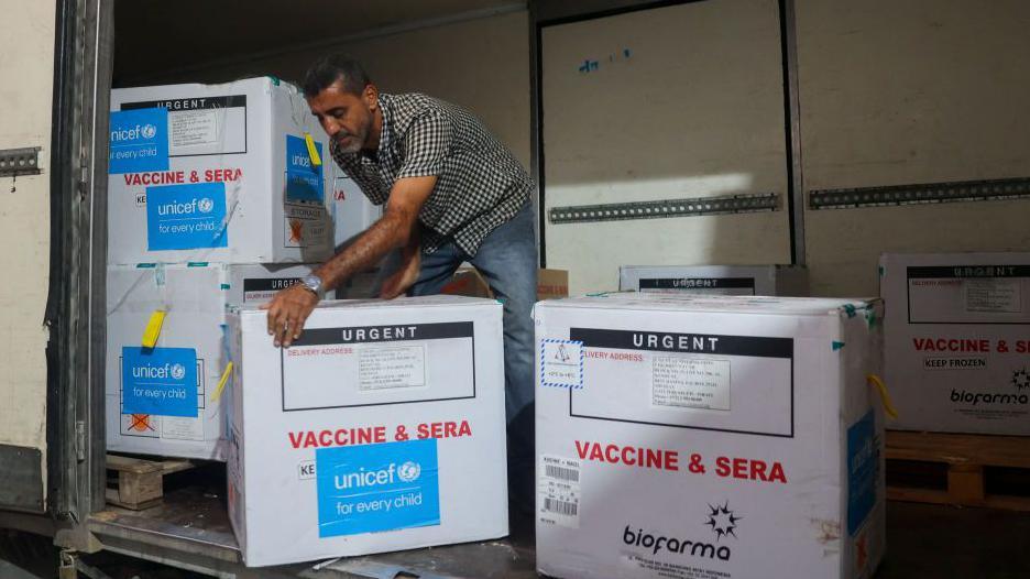 A man unloads a shipment of boxes of polio vaccines provided with support from UNICEF to the Gaza Strip