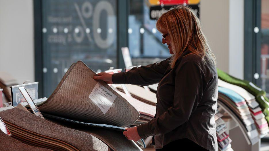 A woman looks at carpets in a shop