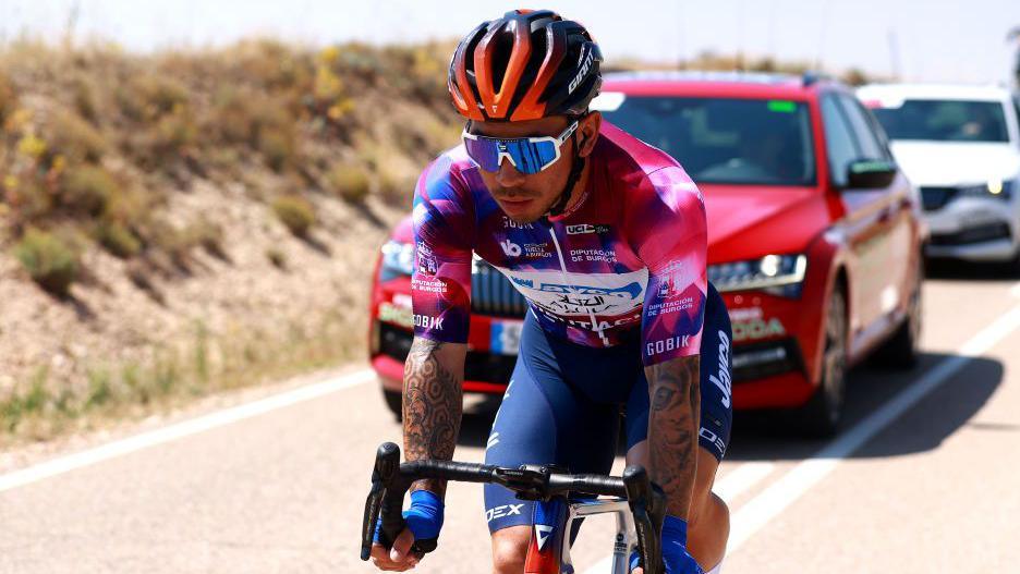 Caleb Ewan rides his bike in front of the convoy of support cars during the Vuelta a Burgos