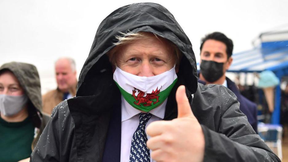 Boris Johnson wearing a mask with the Welsh flag on