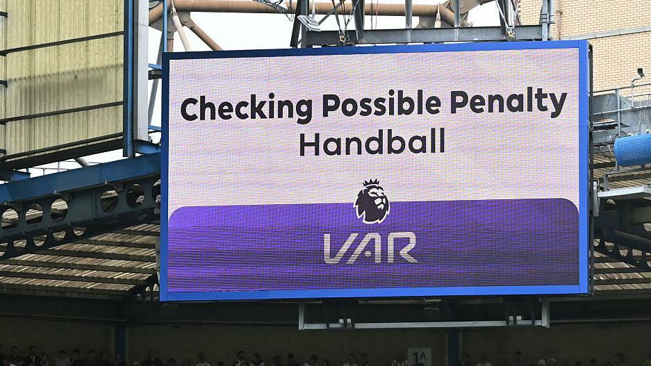 A big screen display a VAR check for a possible penalty during a Premier League match
