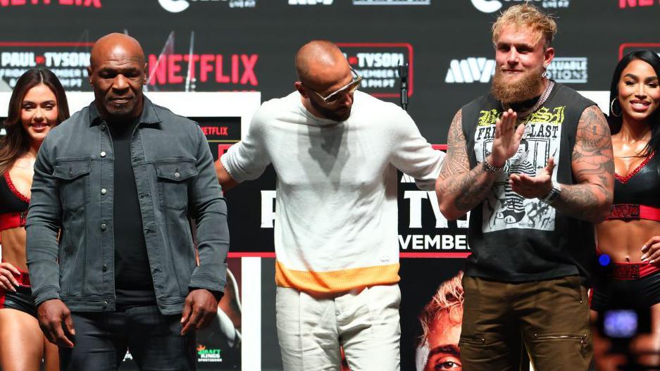 Mike Tyson poses for pictures with a smiling Jake Paul at a news conference