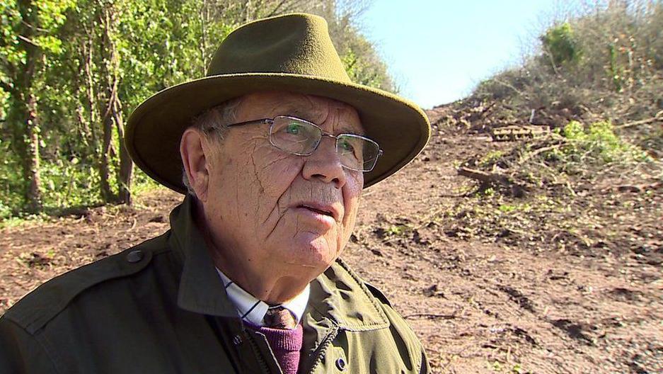 Henry Danter, wearing a brimmed hat and barbour-style jacket on his land