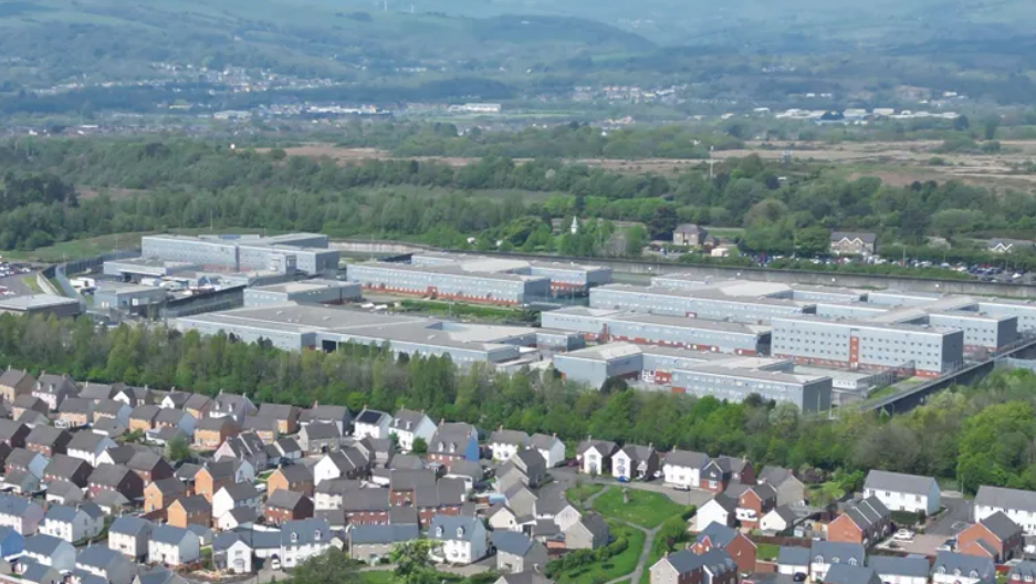 An aerial view of Parc Prison in the background with houses in the foreground 