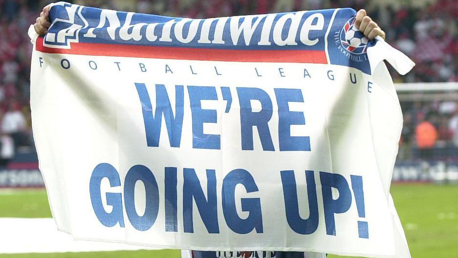 An Ipswich Town player holds up a flag after a successful promotion to the Premier League in 2002