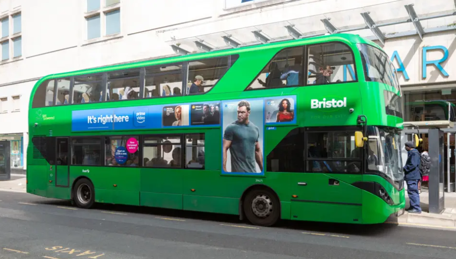 A green First Bus in Bristol outside a Primark store with an Amazon Prime advert on the bus.