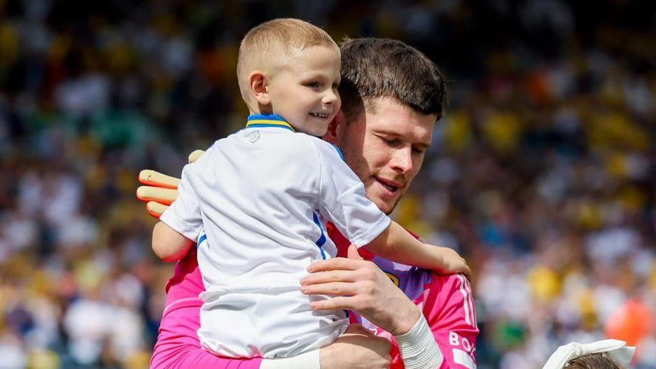 Bob being carried by his favourite player Illan Meslier onto a football pitch