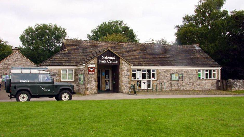 A stone built one storey building with a wooden sign reading National Park Centre