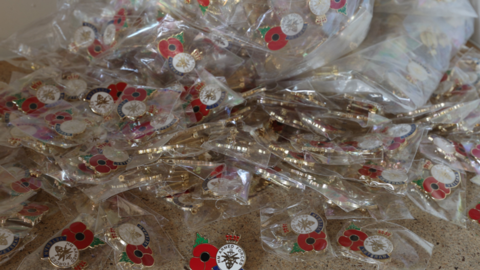 A pile of fake Poppy pin badges in plastic wrapping