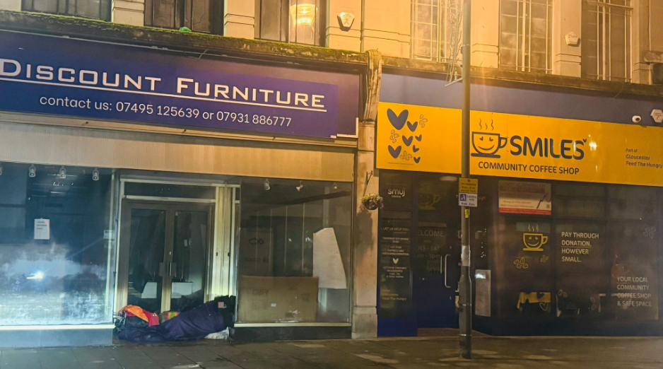 A person sleeping rough on a high street in a closed down shop doorway in a blue sleeping bag 