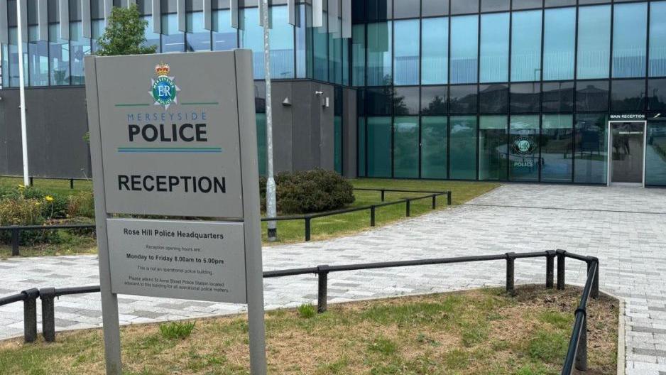 A sign positioned outside Merseyside Police's headquarters. It reads: Merseyside Police Reception - Rose Hill Police Headquarters". 