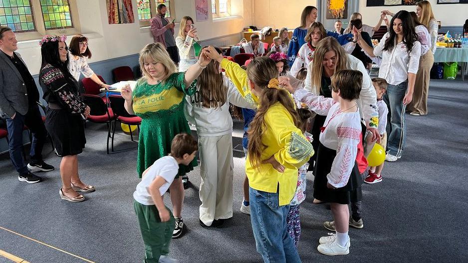 Two lines of children with some parents learning a dance