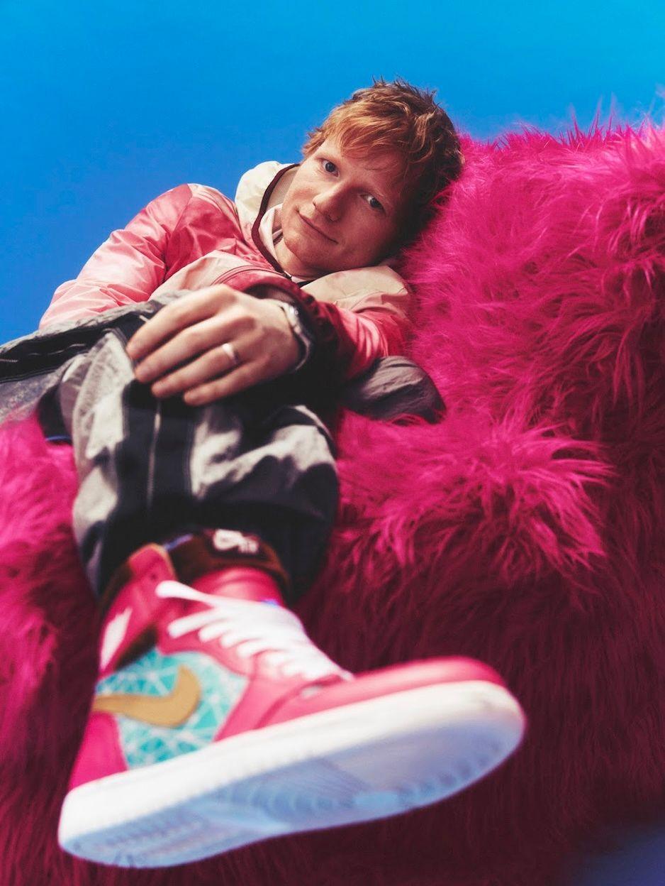 Ed Sheeran reclines on a fluffy pink chair, with his head turned to the camera 
