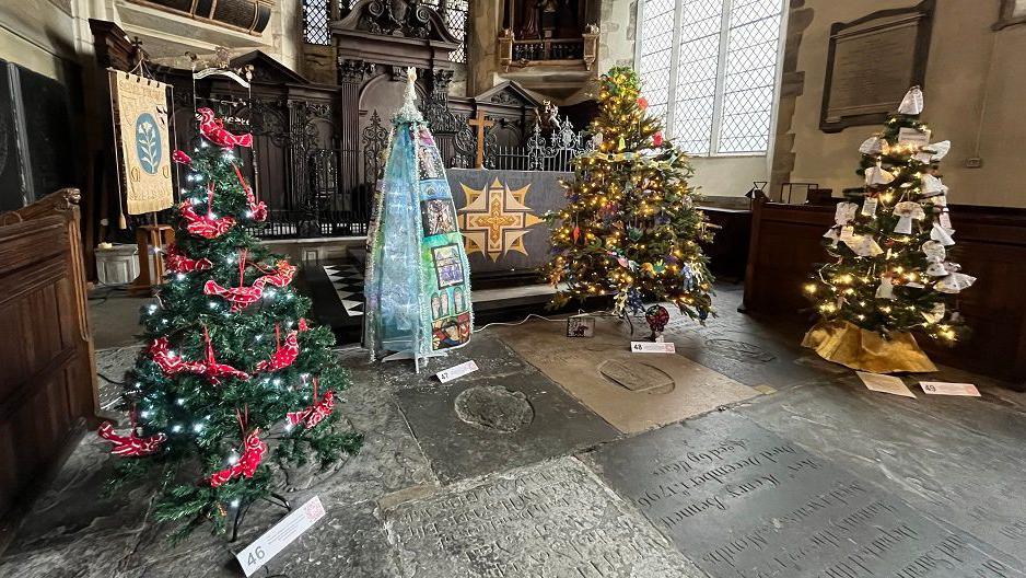 A section of chapel to the side of the main nave of the church with four larger trees.